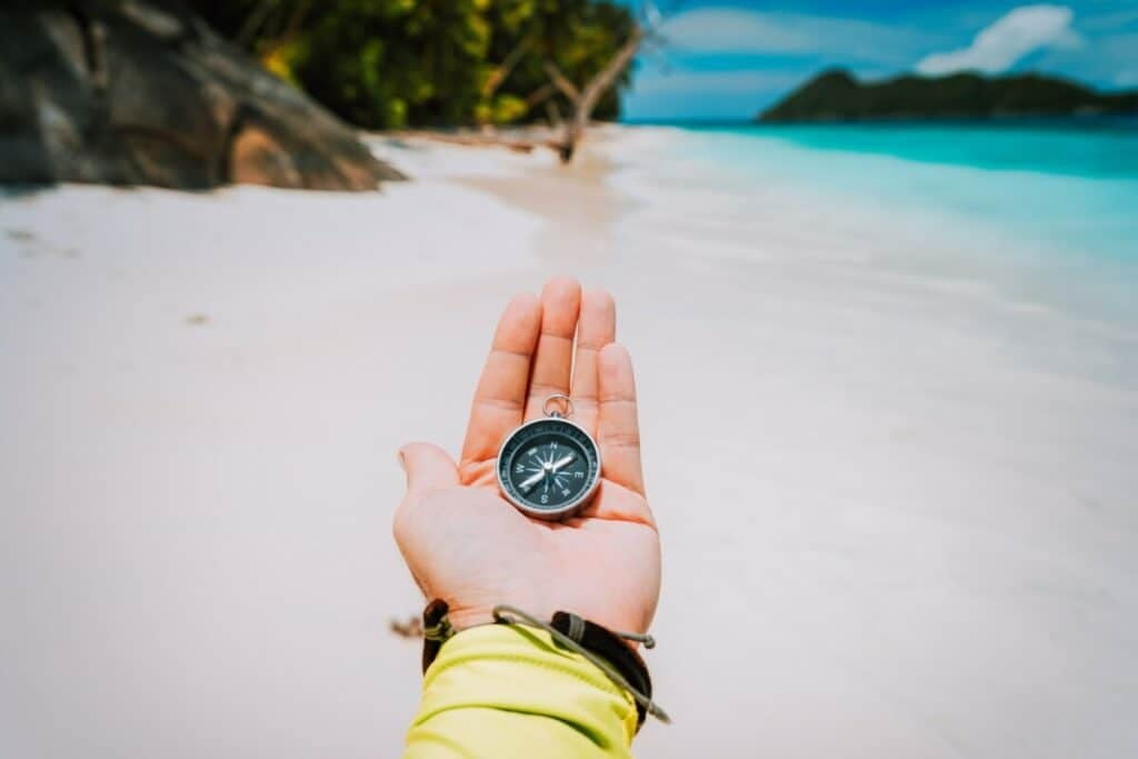 beach with hand holding compass